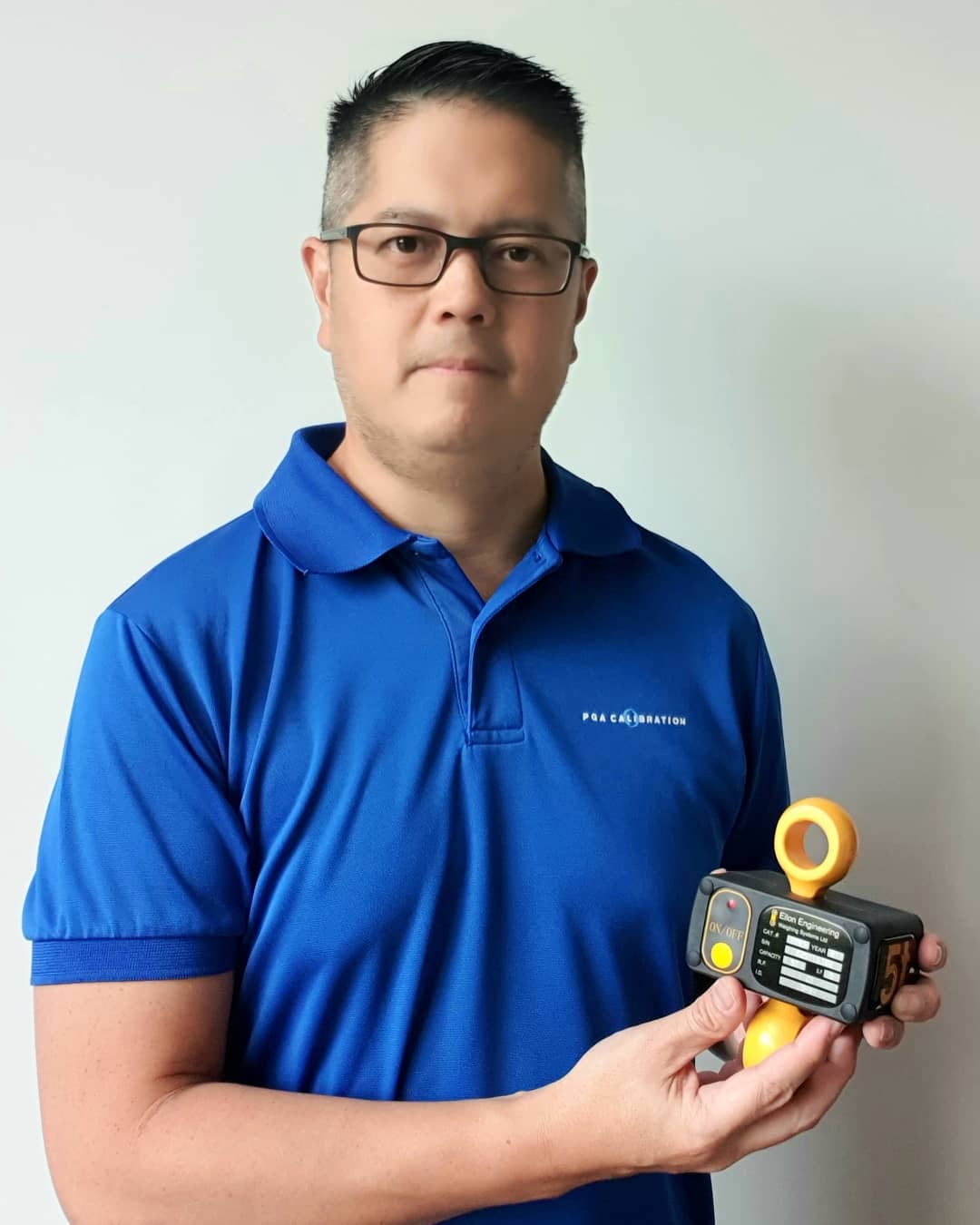 Man in blue shirt holding a 1-ton Eilon Engineering load cell