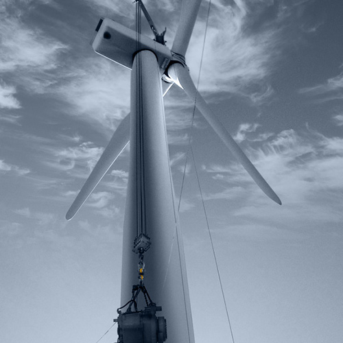 A gearbox is hoisted up a wind turbine tower
